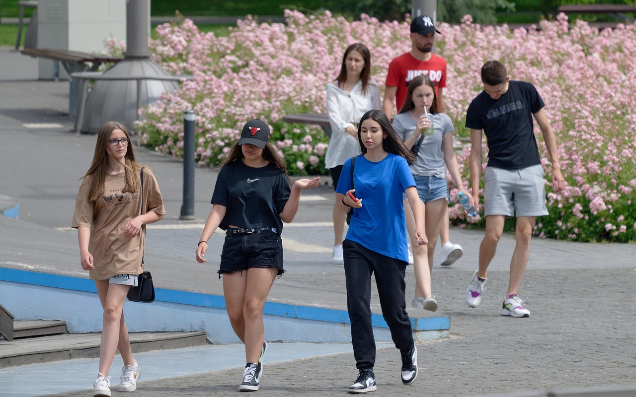 Due giovani studenti discutono su una scrivania con libri, simbolo di supporto economico per i figli maggiorenni.