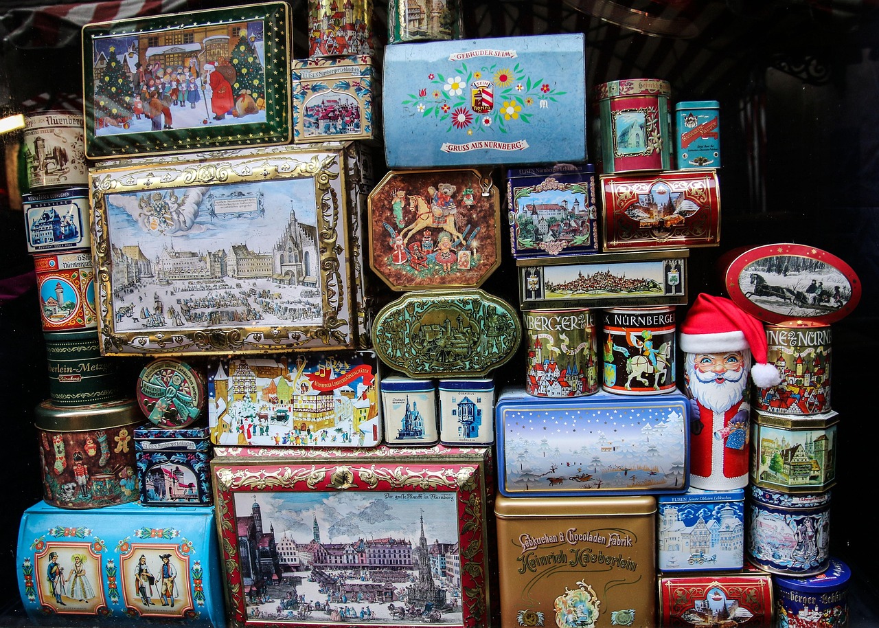 Vecchie scatole di latta pubblicitarie vintage, colorate e decorate, esposte su uno sfondo neutro.