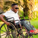 Disabile in carrozzina che consulta documenti per richiedere esenzione bollo auto.